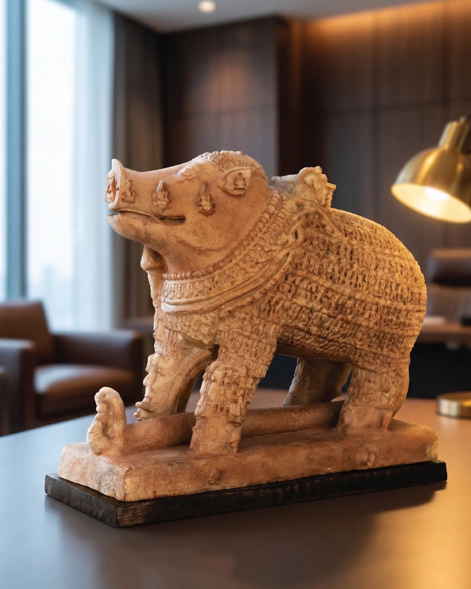 A side-profile view of the Adi Varaha Sculpture, a sandstone-textured replica featuring intricate carvings of the boar-headed Vishnu avatar.