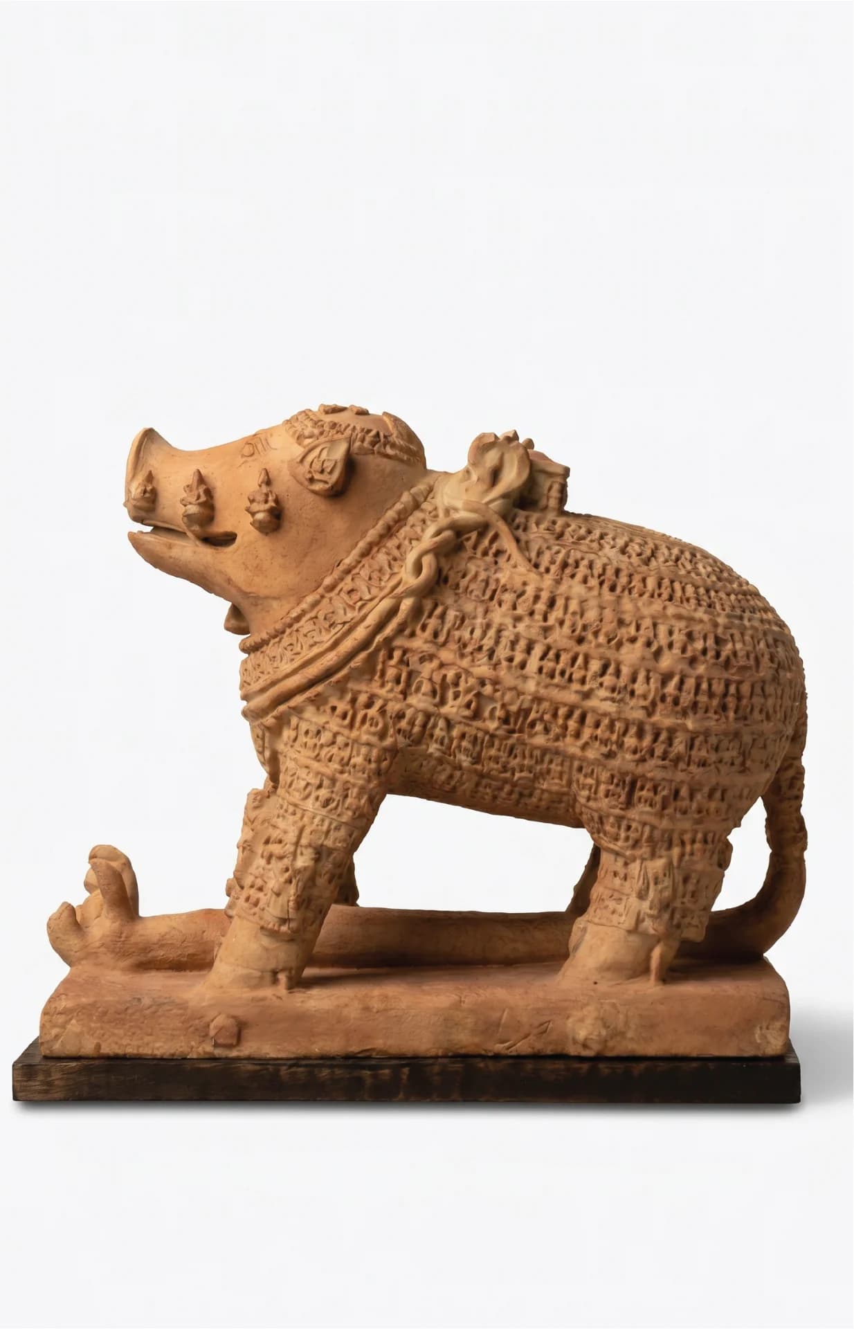 A side-profile view of the Adi Varaha Sculpture, a terracotta-style replica featuring intricate carvings of divine figures across its body.