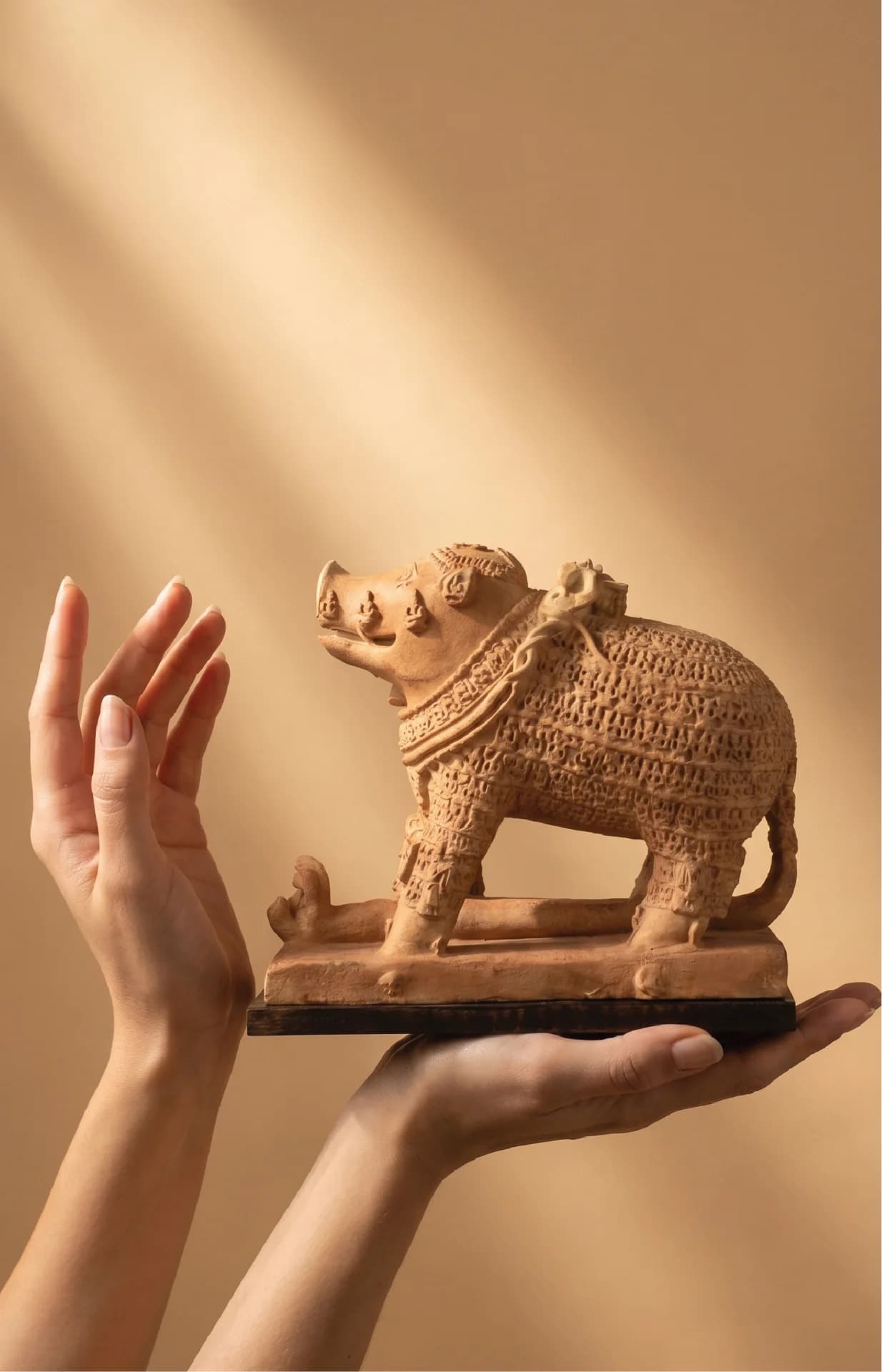 A person holds a terracotta-style Adi Varaha Sculpture replica, showcasing the intricate carved details of the mythical boar deity.