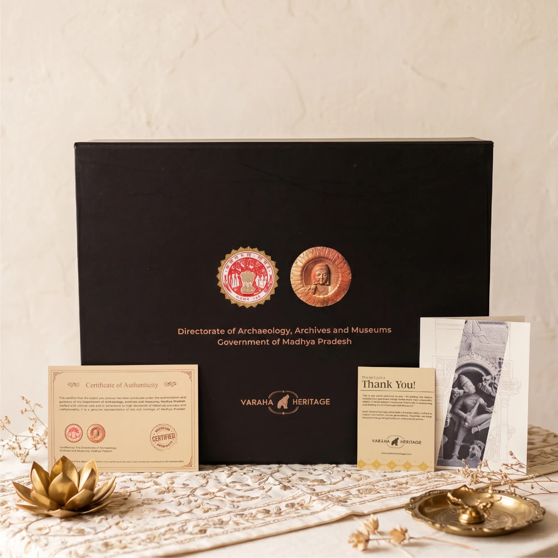 The Gajasura Vadha Sculpture packaging box featuring museum certification and authenticity documents displayed on an ornate fabric surface.