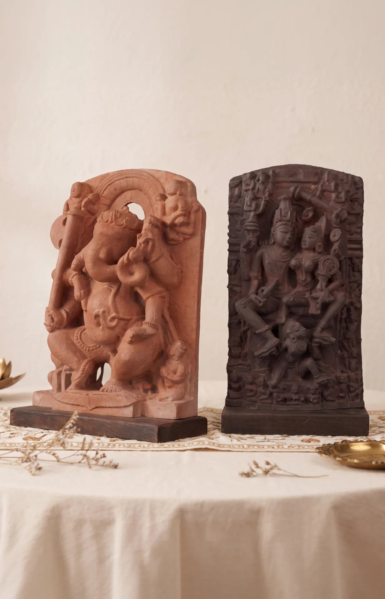 A ganesha laxmi narayan combo featuring two intricately carved terracotta statues displayed side-by-side on a white table.
