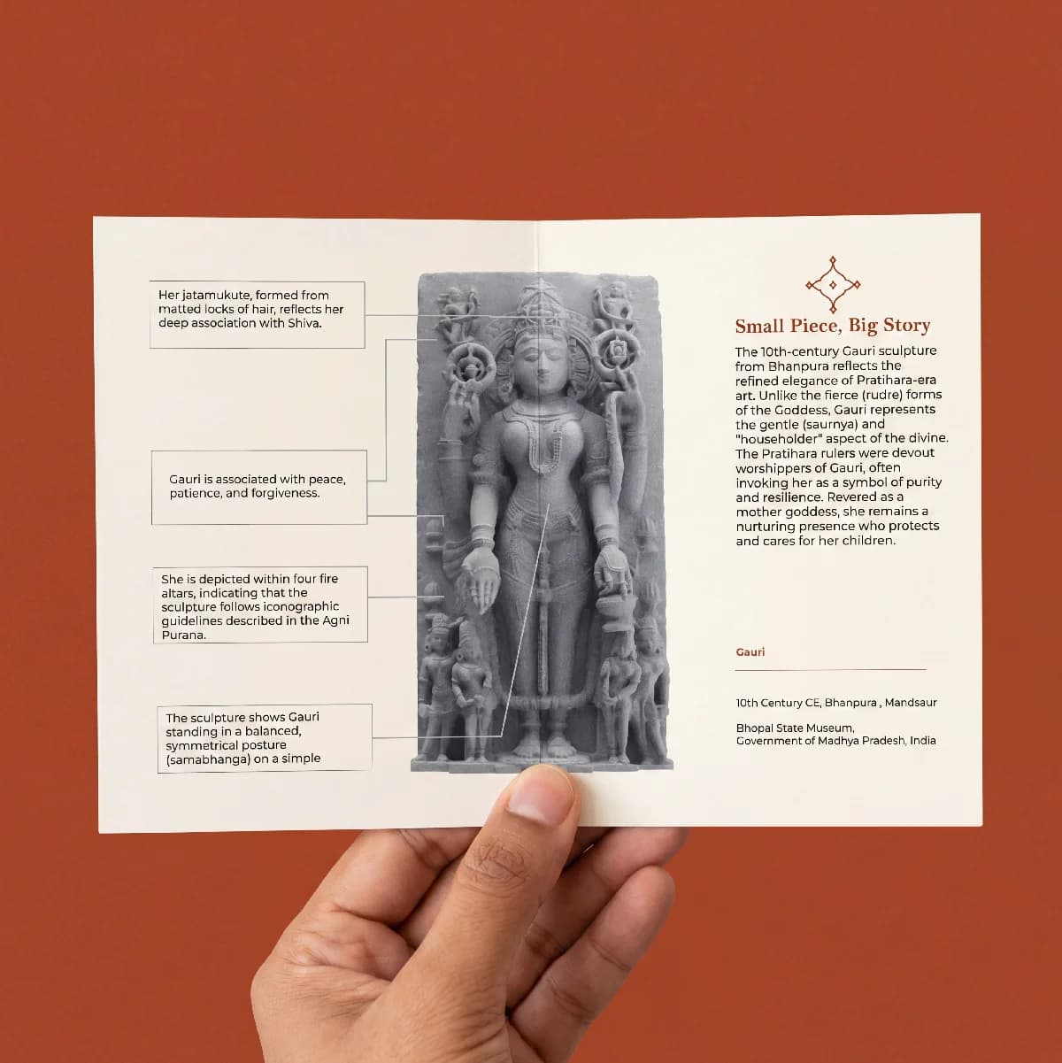 A hand holds an informational brochure featuring the Gauri Parvati Sculpture, highlighting its stone composite texture and iconography.