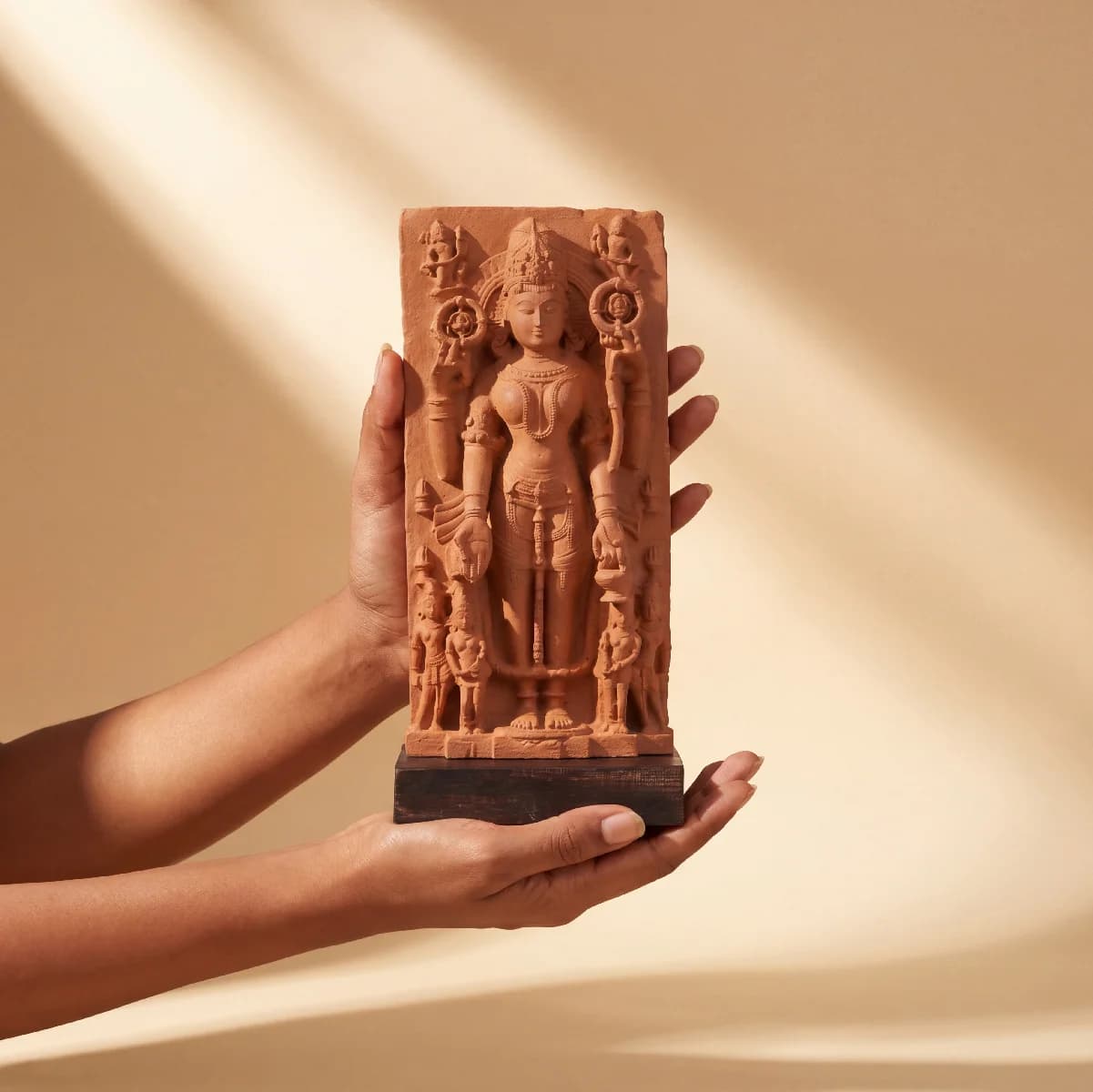 A pair of hands holds a Gauri Parvati Sculpture, a hand-finished stone composite replica featuring detailed Hindu temple art.