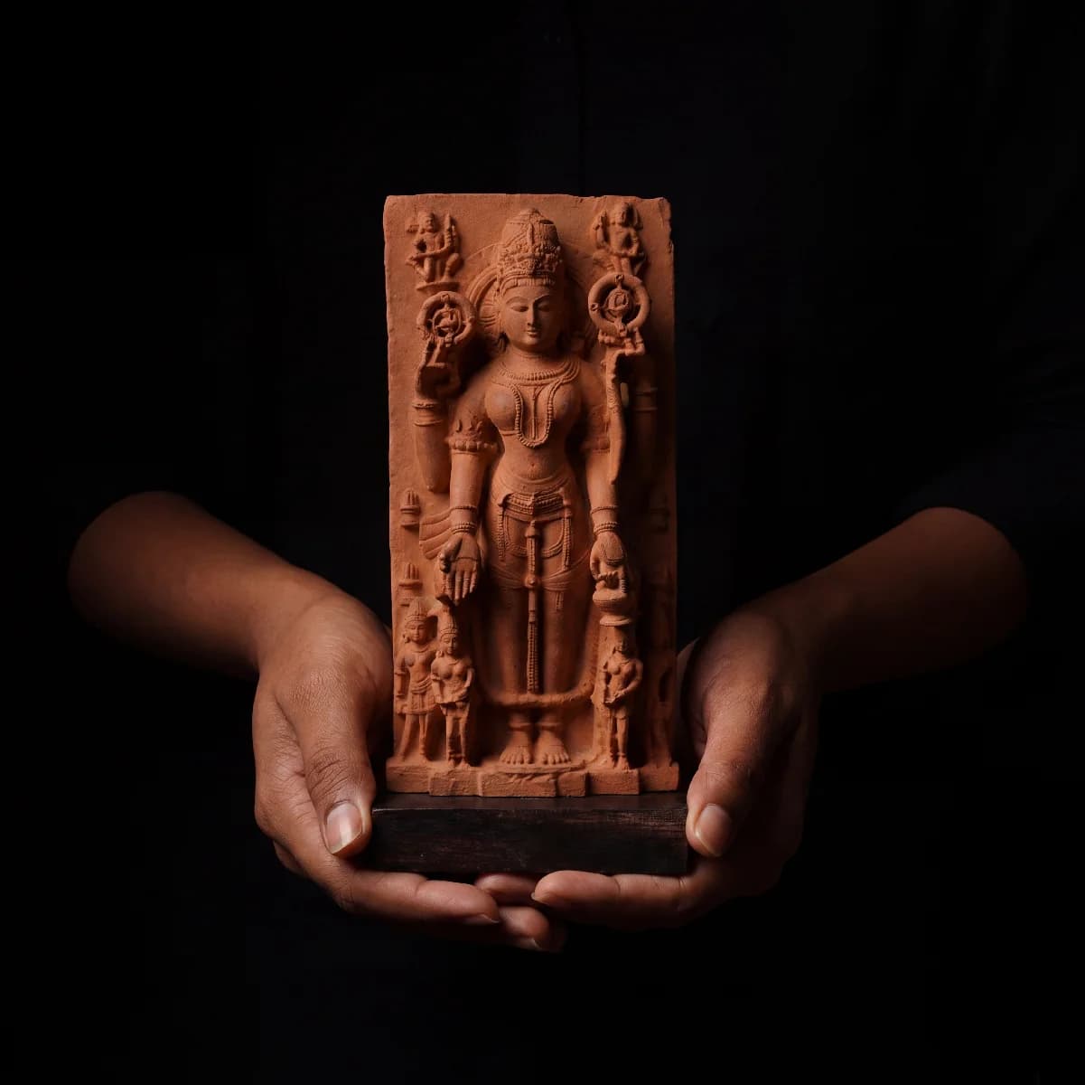 A pair of hands holds a stone composite Gauri Parvati Sculpture, showcasing the detailed 10th-century Pratihara temple art style.