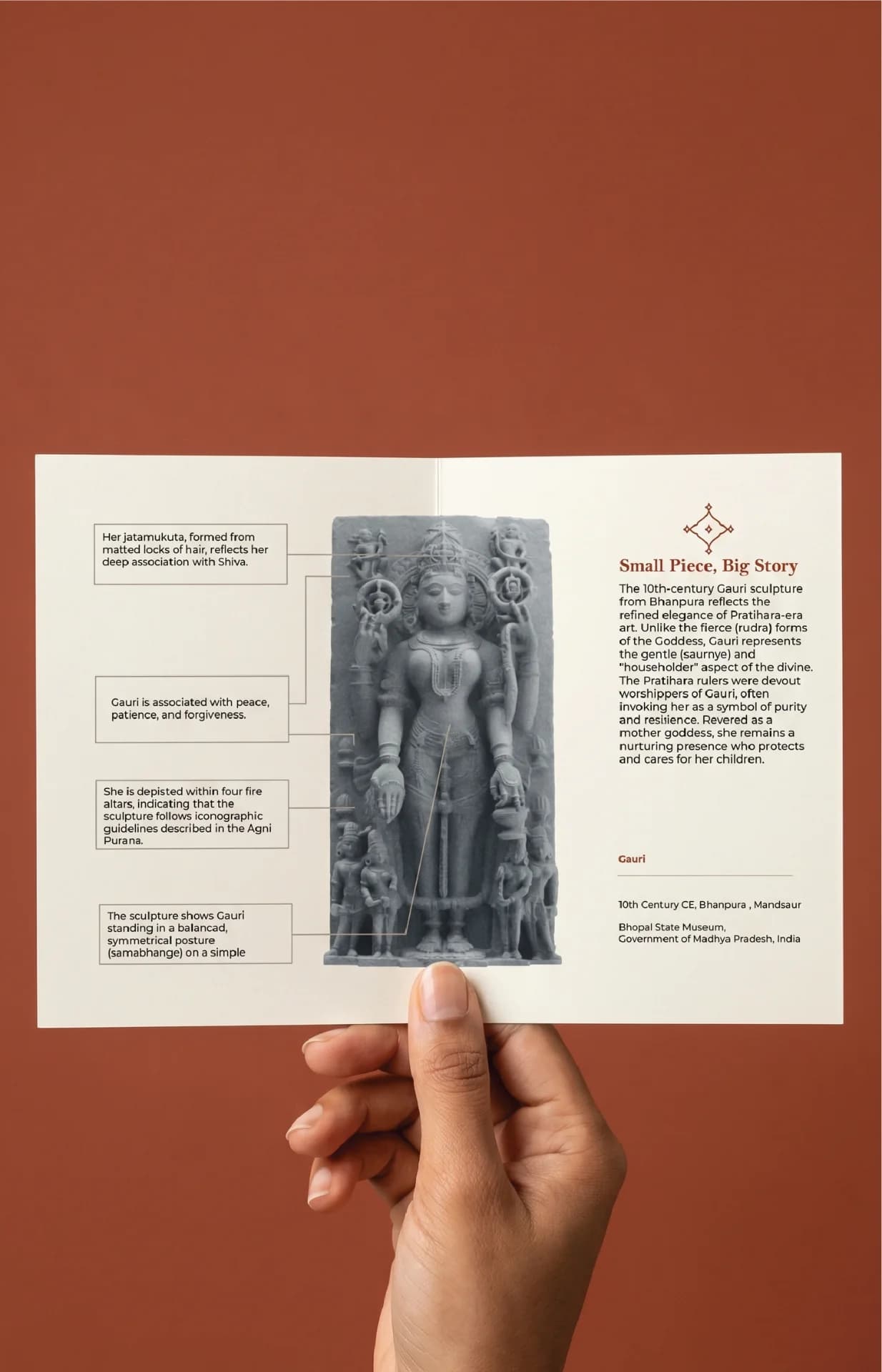 A hand holds an informational brochure featuring the Gauri Parvati Sculpture, a stone composite replica with detailed historical annotations.