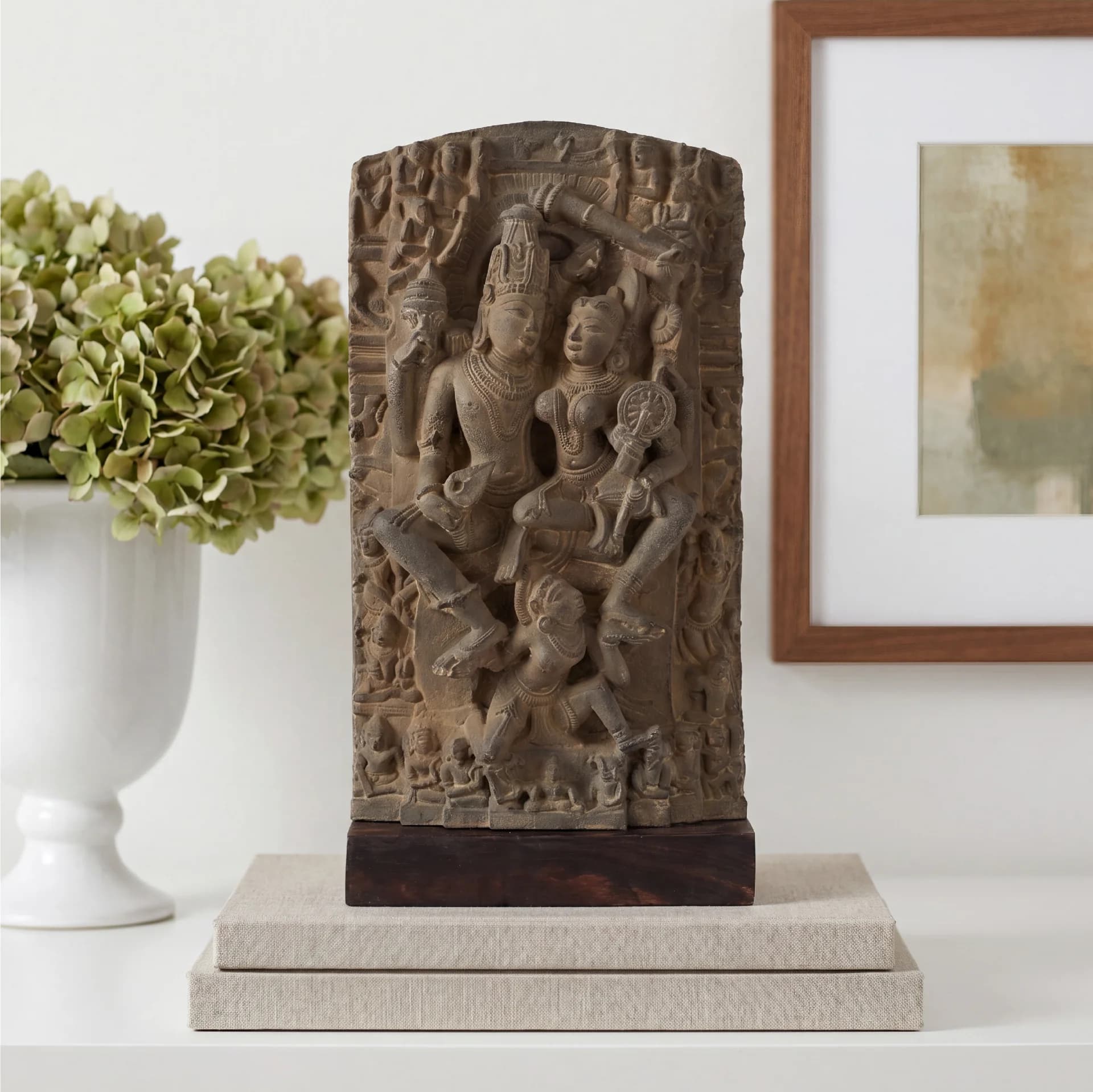 A detailed stone Lakshmi Narayan Sculpture displayed on books, featuring intricate 12th-century style carvings of the divine couple.