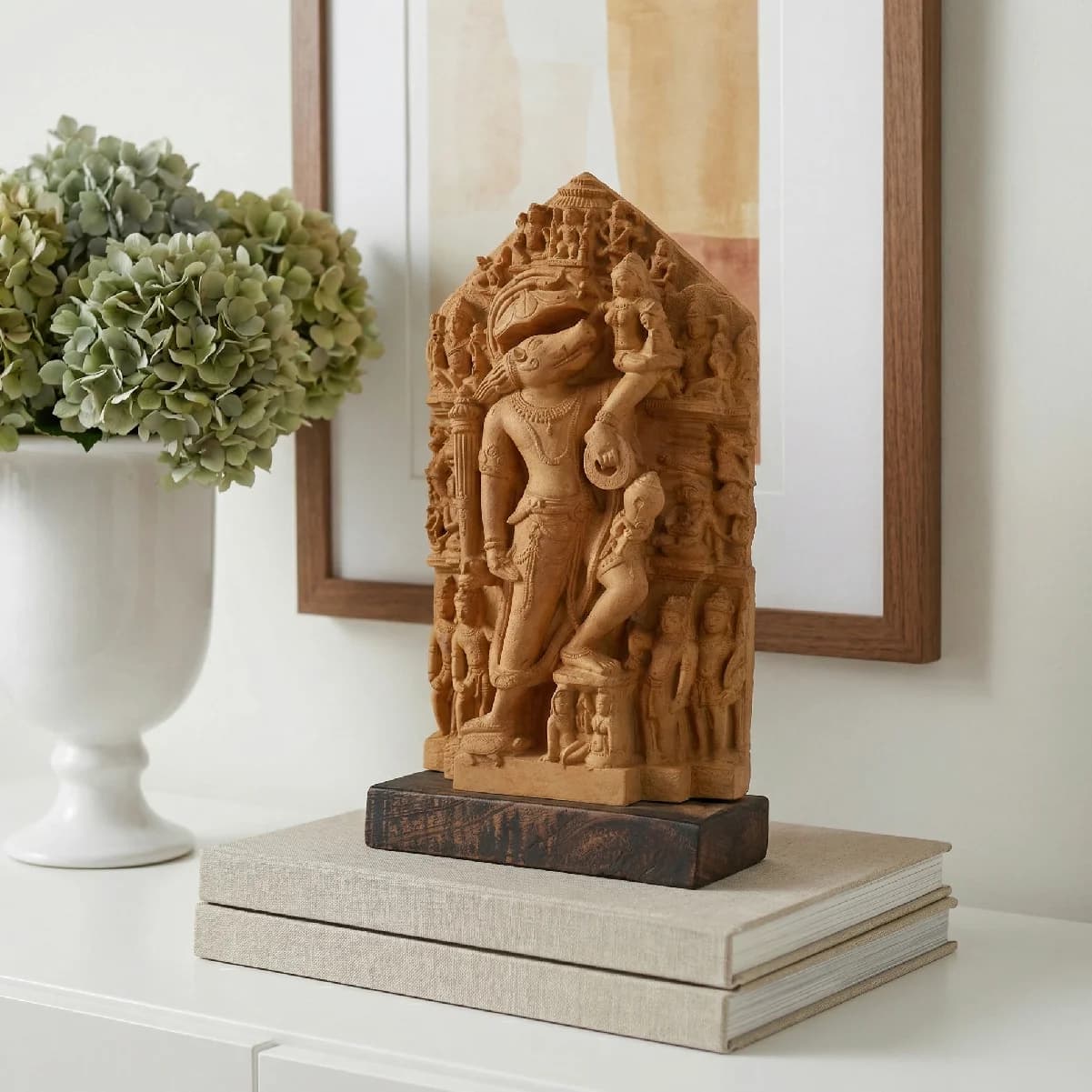 The Nar Varaha Sculpture, a detailed stone composite replica, stands elegantly on a stack of books in a home setting.