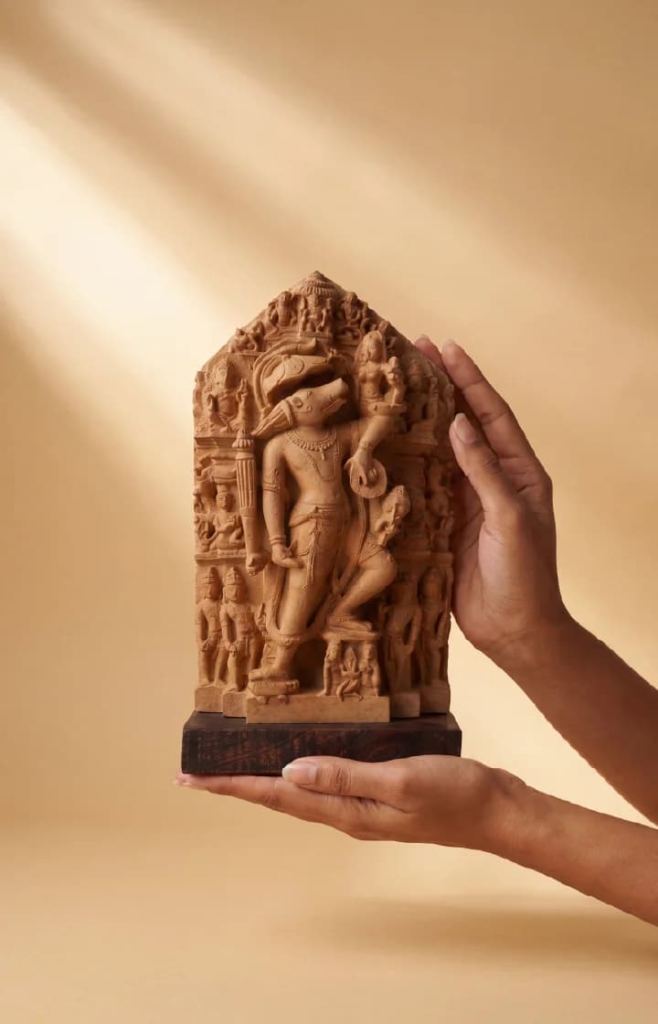 Hands holding a stone composite Nar Varaha Sculpture, showcasing the intricate 10th-century temple art replica details against a neutral background.