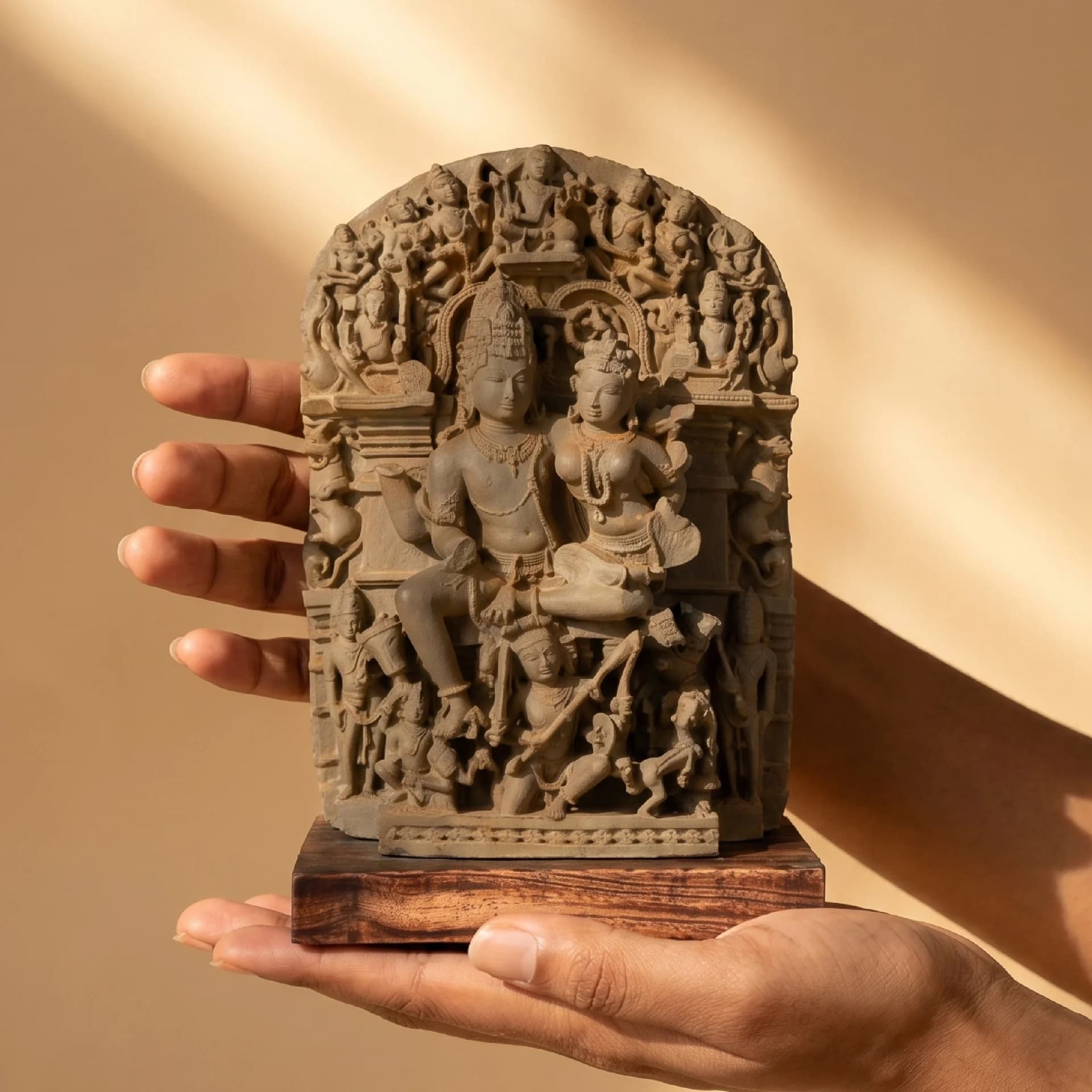 A pair of hands holds a stone composite Ravananugraha Sculpture replica, showcasing the intricate 11th-century temple art details.