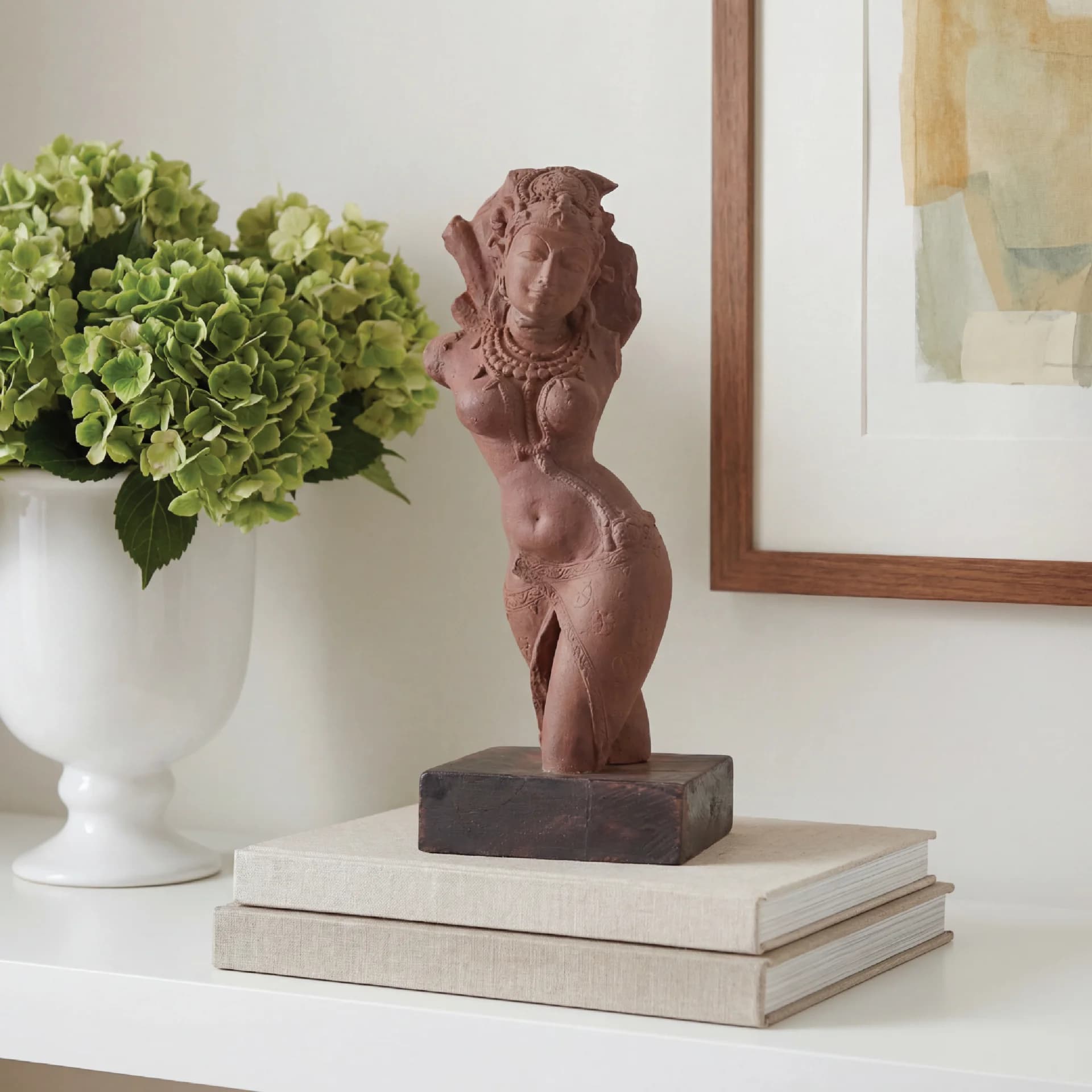 The Salabhanjika Sculpture displayed on a stack of books, featuring a hand-finished stone composite figure in an elegant pose.