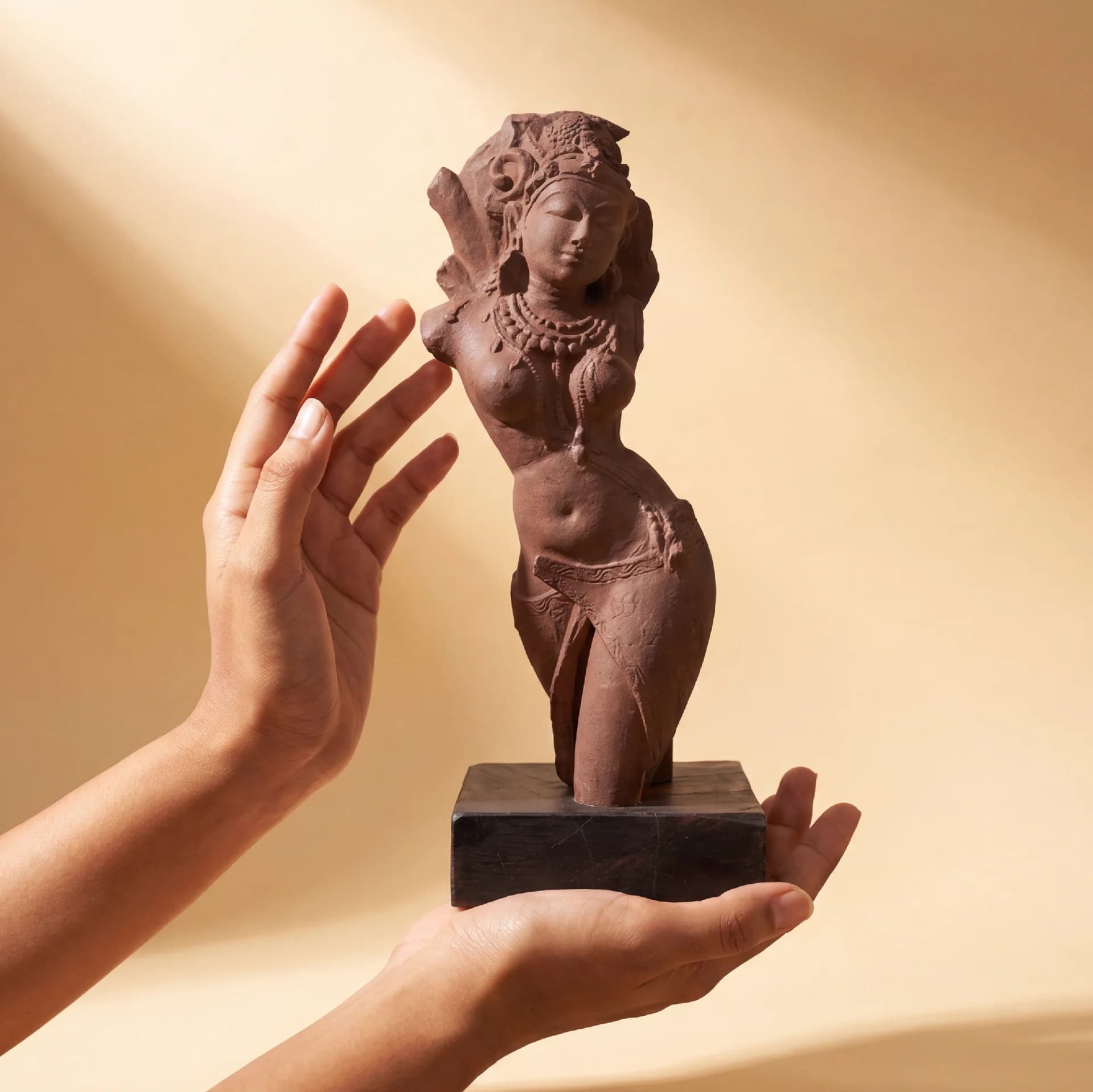 A pair of hands gently cradles a stone composite Salabhanjika Sculpture, highlighting the intricate craftsmanship of this museum-replica art piece.