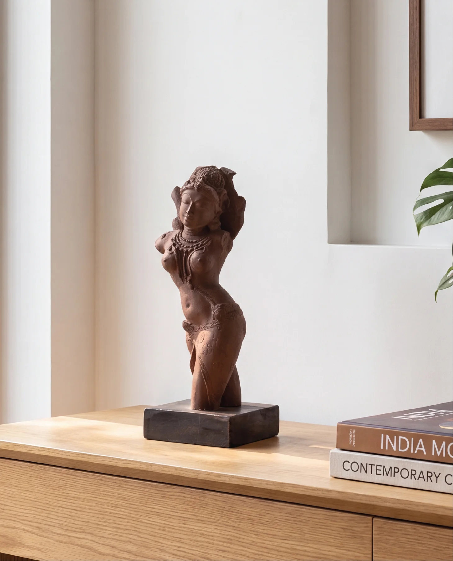 A Salabhanjika Sculpture replica crafted from stone composite, displayed on a wooden base in a bright, modern interior setting.