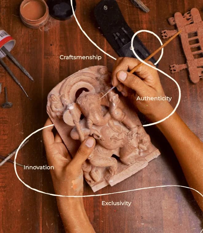 An artisan uses a fine tool to carve intricate details into a terracotta Ganesha statue on a wooden workbench.