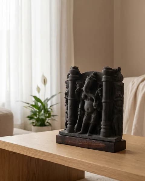 A dark stone Vinayaki Sculpture replica displayed on a wooden table, showcasing intricate 11th-century temple art details.