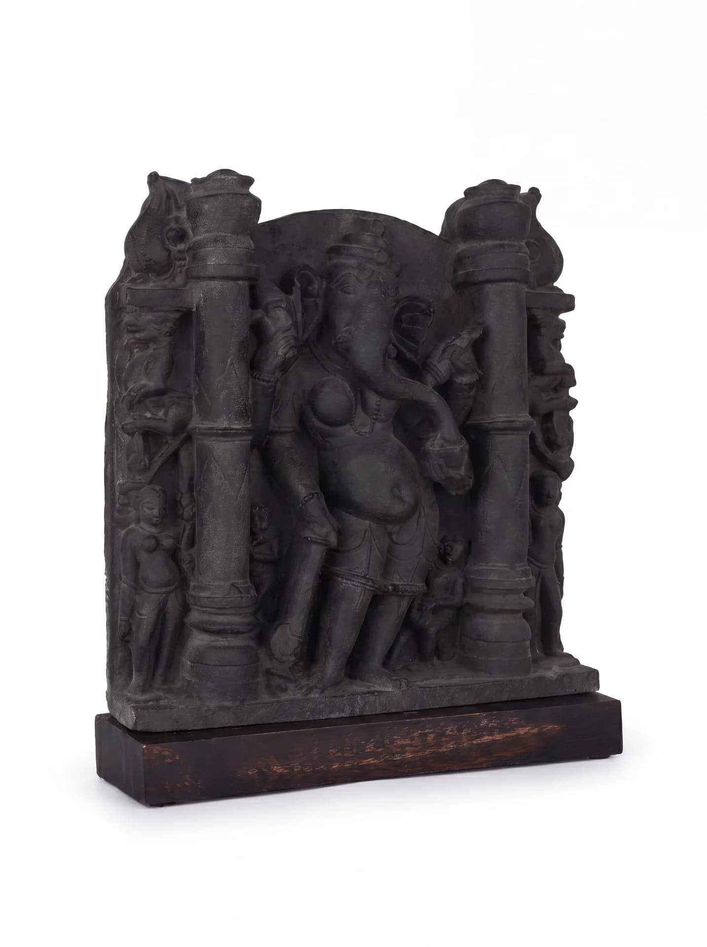 A three-quarter view of the Vinayaki Sculpture, a dark stone-finish replica featuring intricate temple carvings on a wooden base.