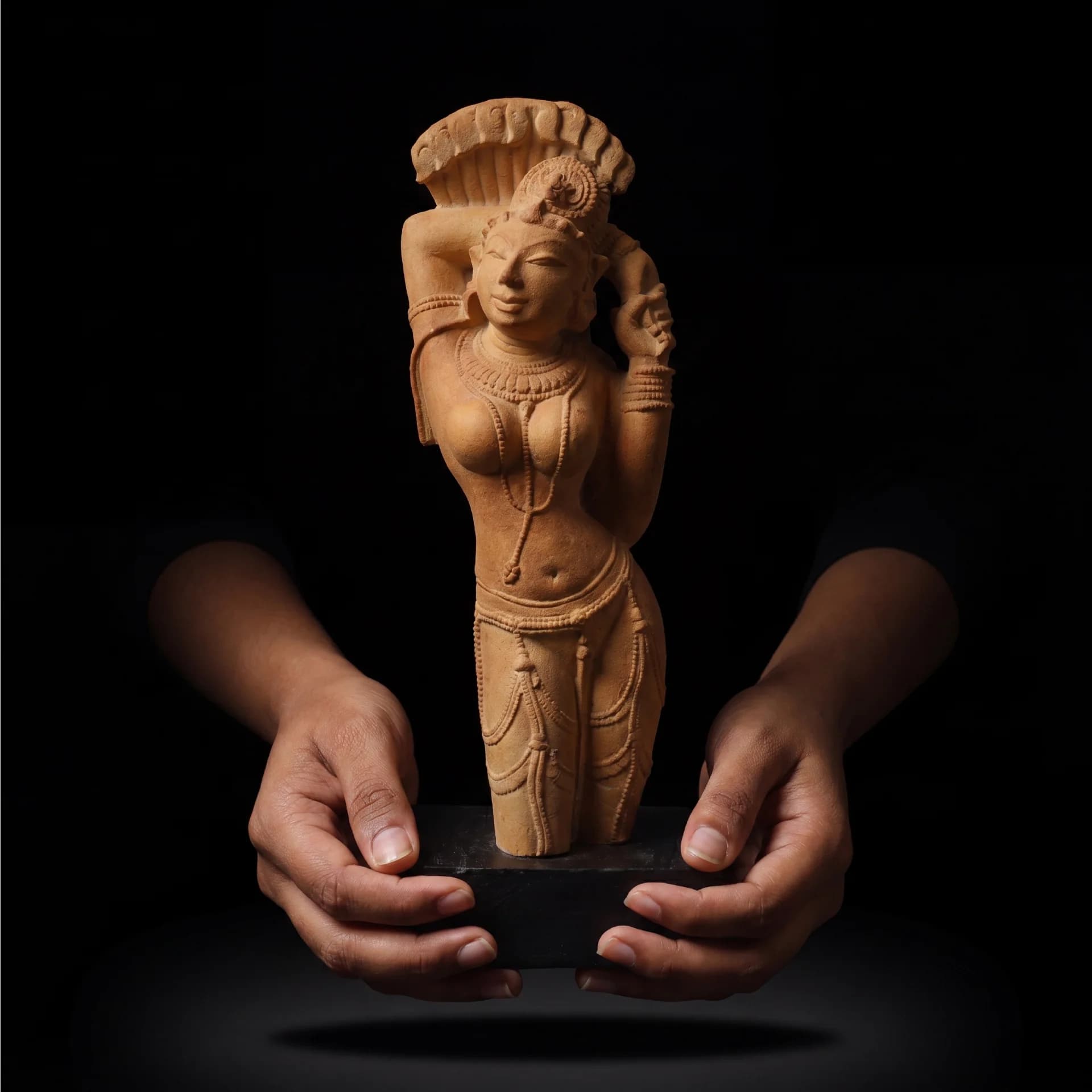 Two hands gently hold the Alasa Nayika Sculpture, a sandstone-style replica featuring intricate traditional Indian temple carving details.