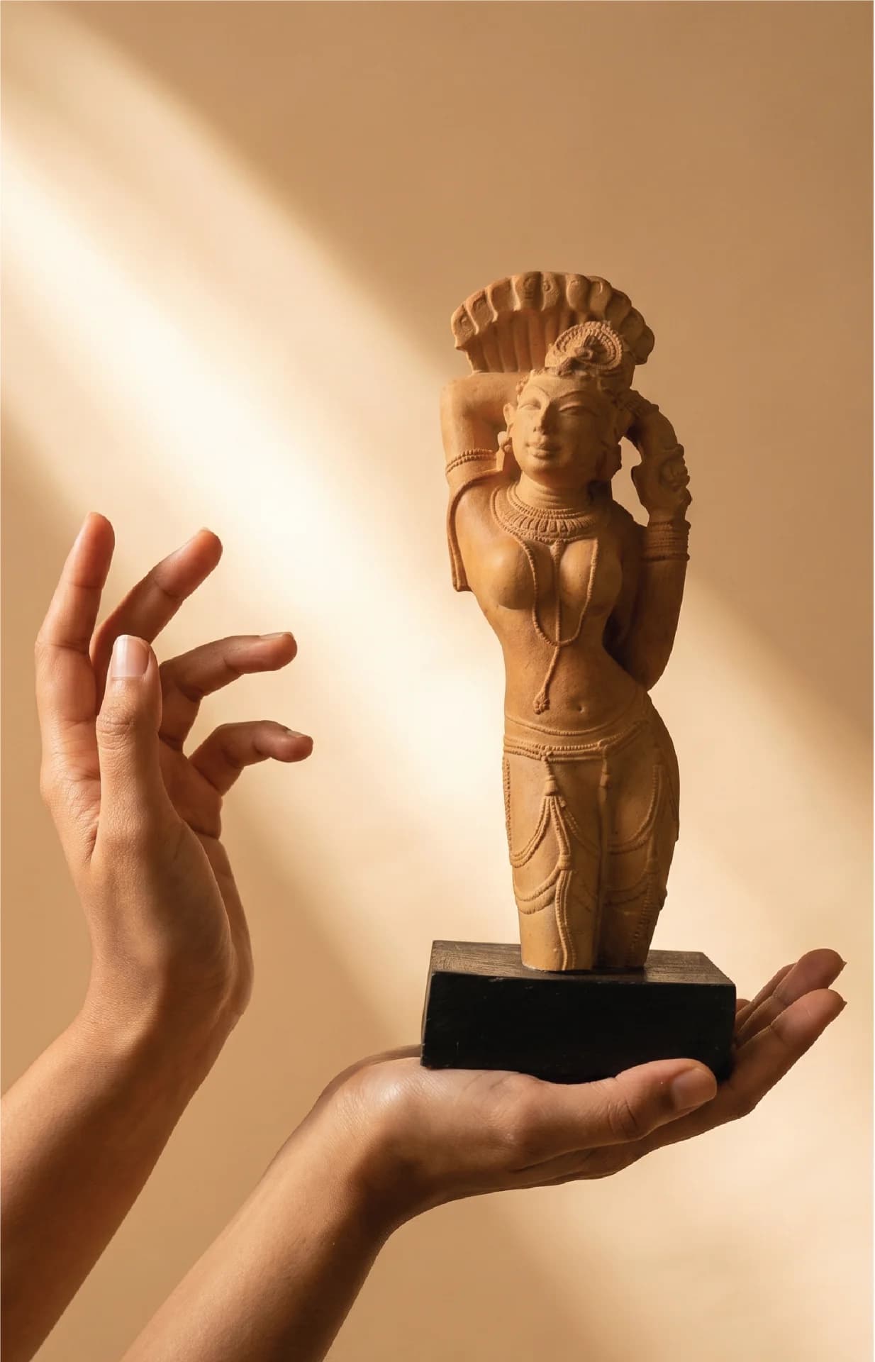 A pair of hands gently cradles the Alasa Nayika Sculpture, a finely carved terracotta-style replica featuring intricate traditional Indian temple jewelry.