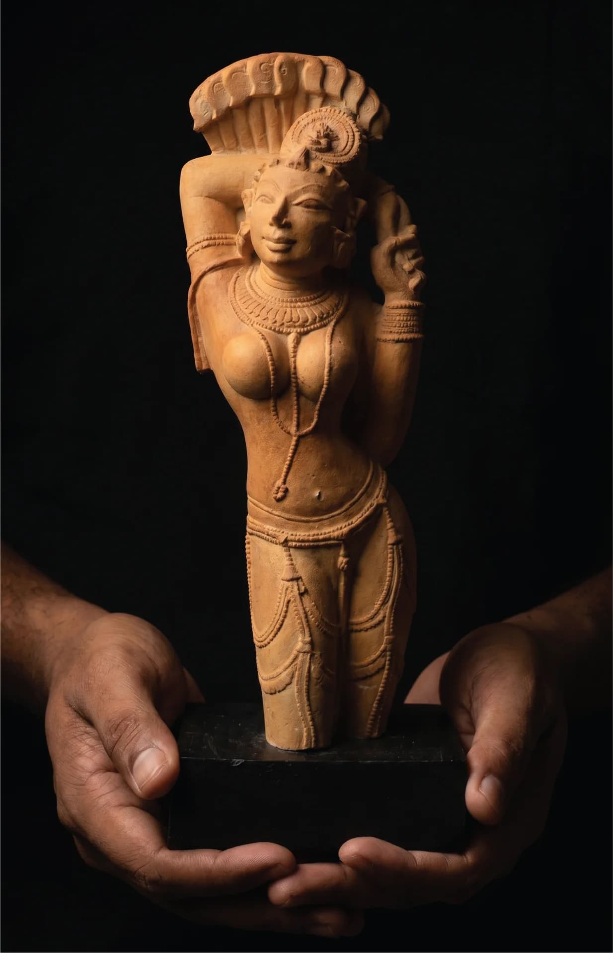 Close-up of hands holding the Alasa Nayika Sculpture, a terracotta-style replica showcasing intricate 10th-century Indian temple art details.