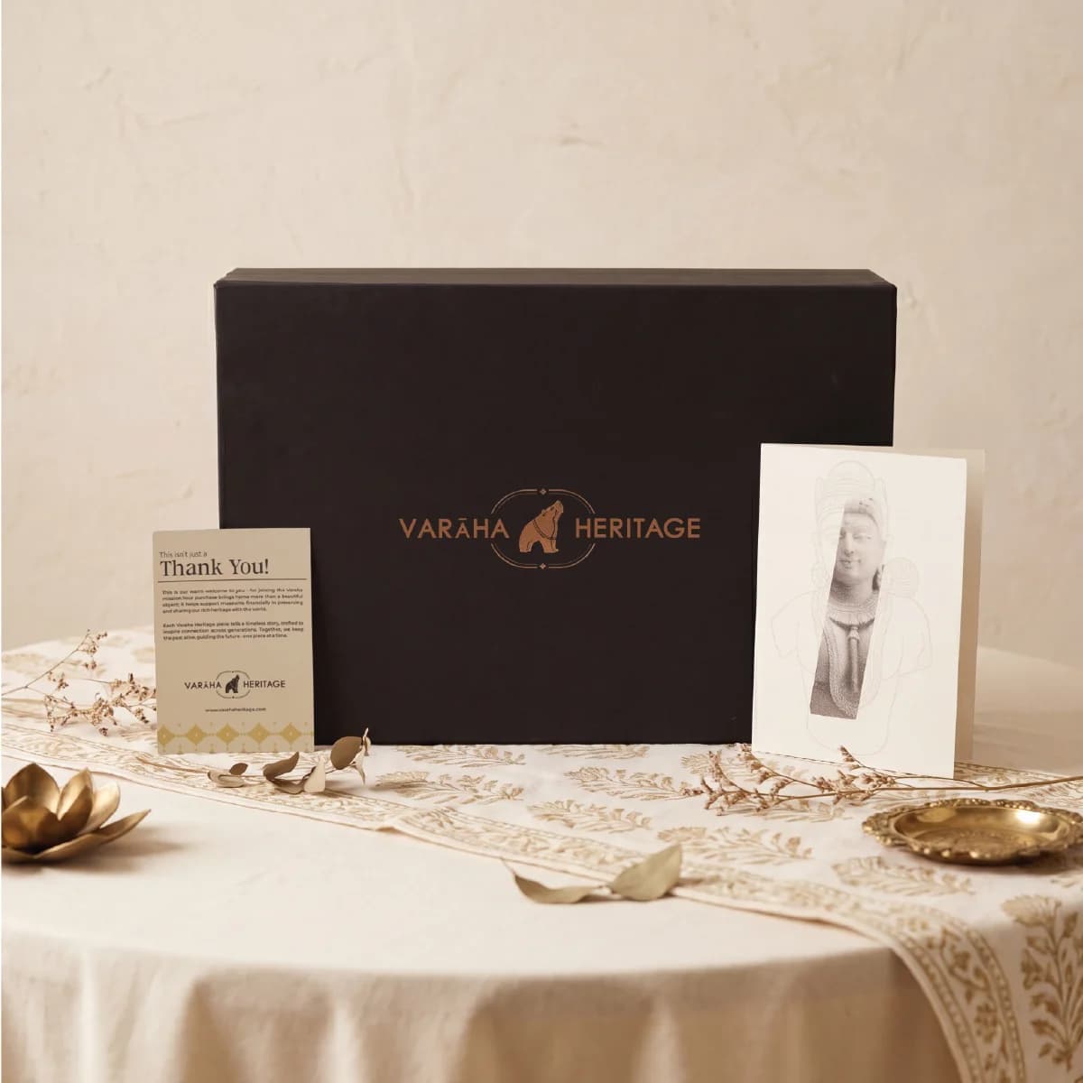 A black gift box for the Female Figure Bust Sculpture, featuring a thank you note and illustrated card on a table.