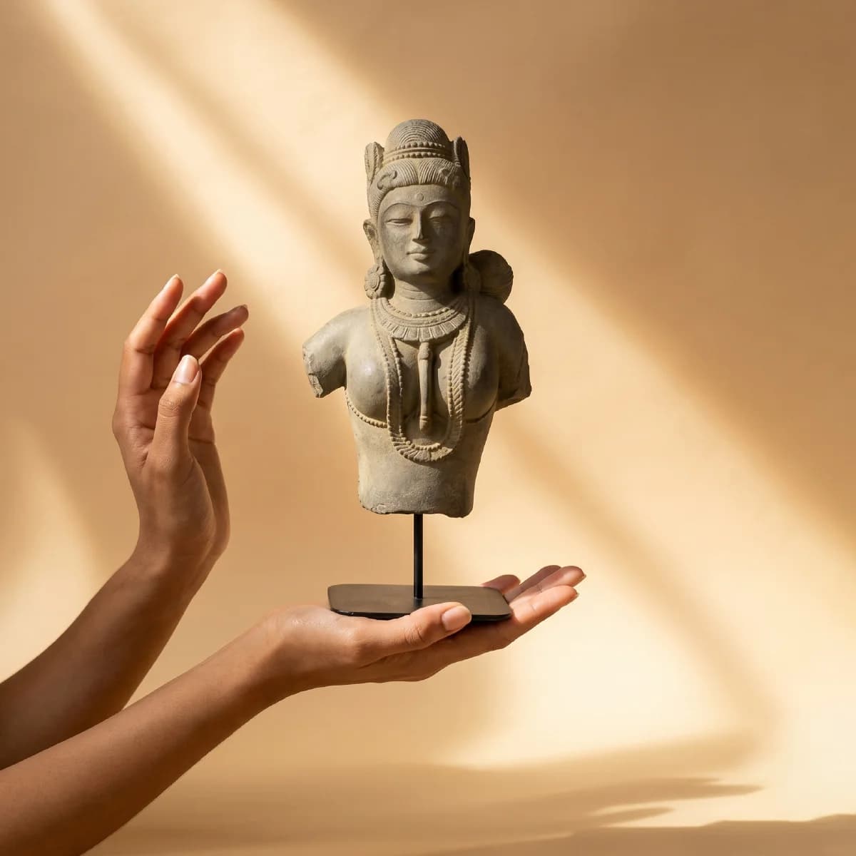 Hands gently cradle a stone composite Female Figure Bust Sculpture, showcasing the detailed Chola style craftsmanship against a warm background.