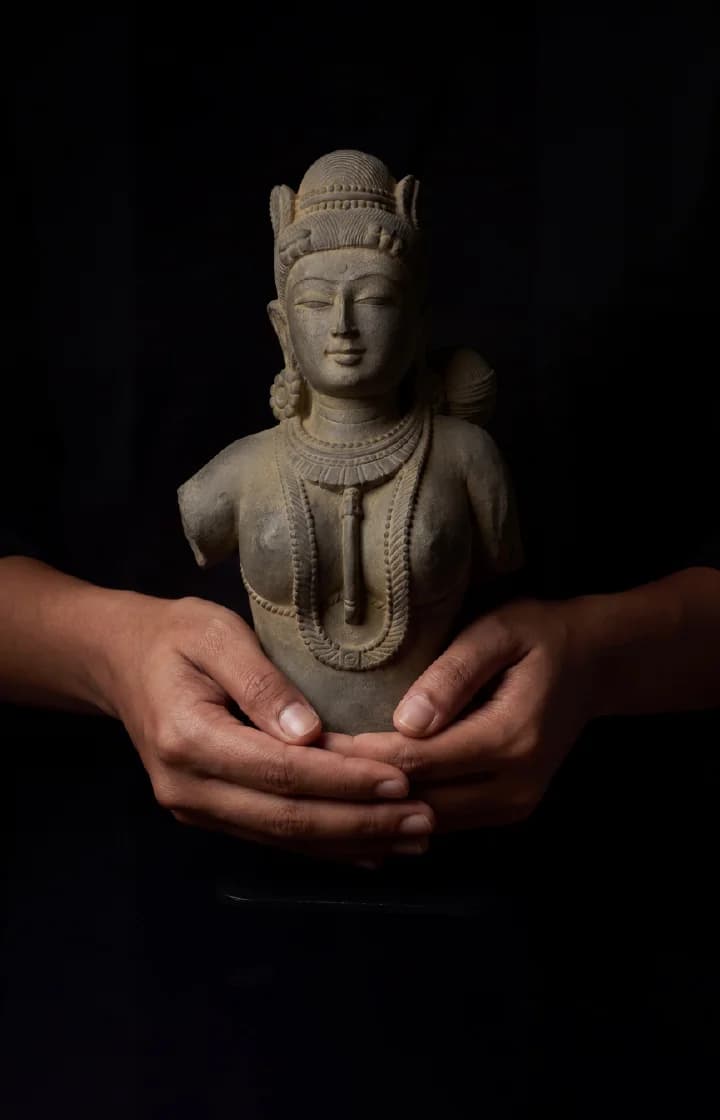 A pair of hands cradles a Female Figure Bust Sculpture, showcasing the intricate stone composite detail and Chola style.