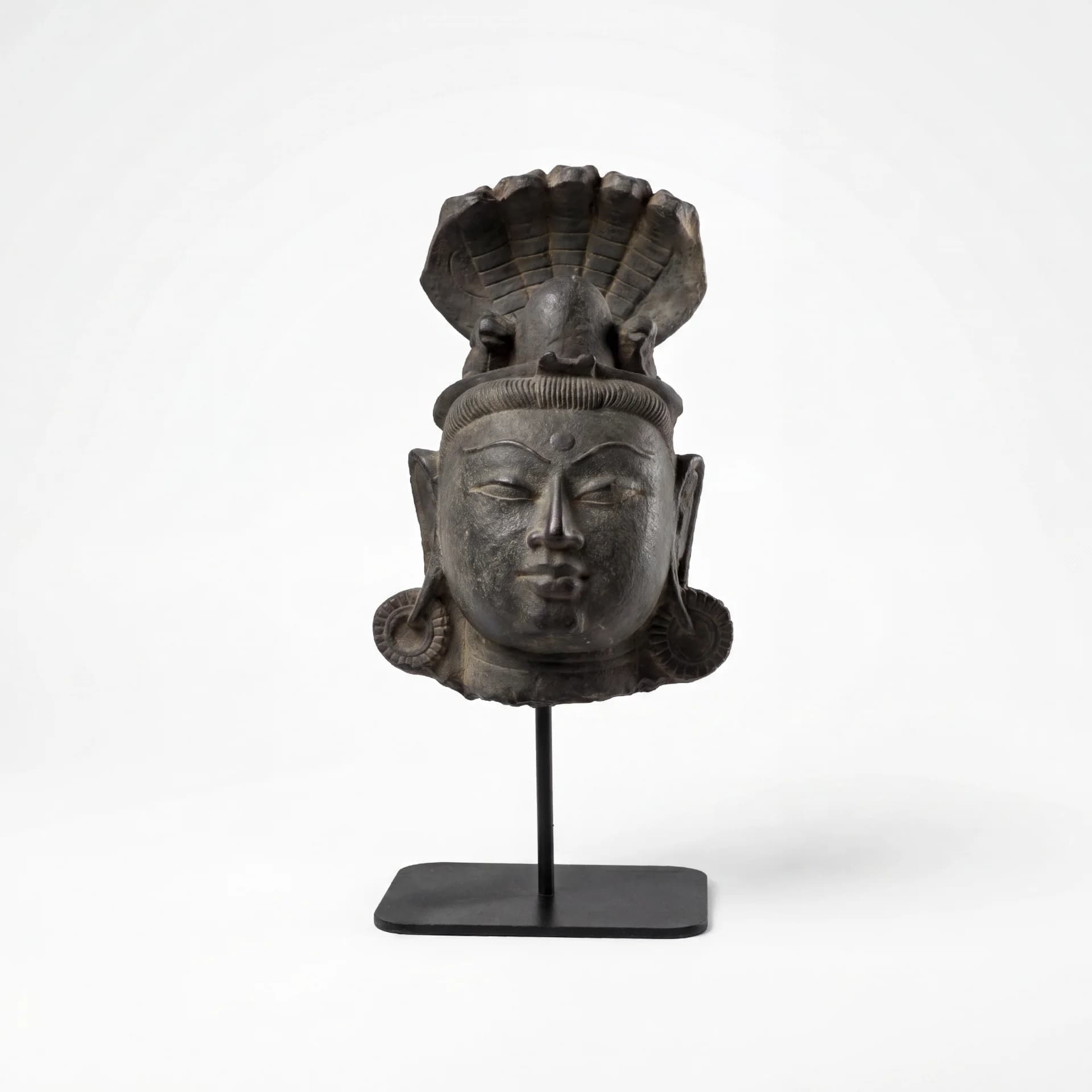 A front-facing view of the Shiva Lingam with Nandi & Serpent replica, featuring a serene stone composite head sculpture on a stand.