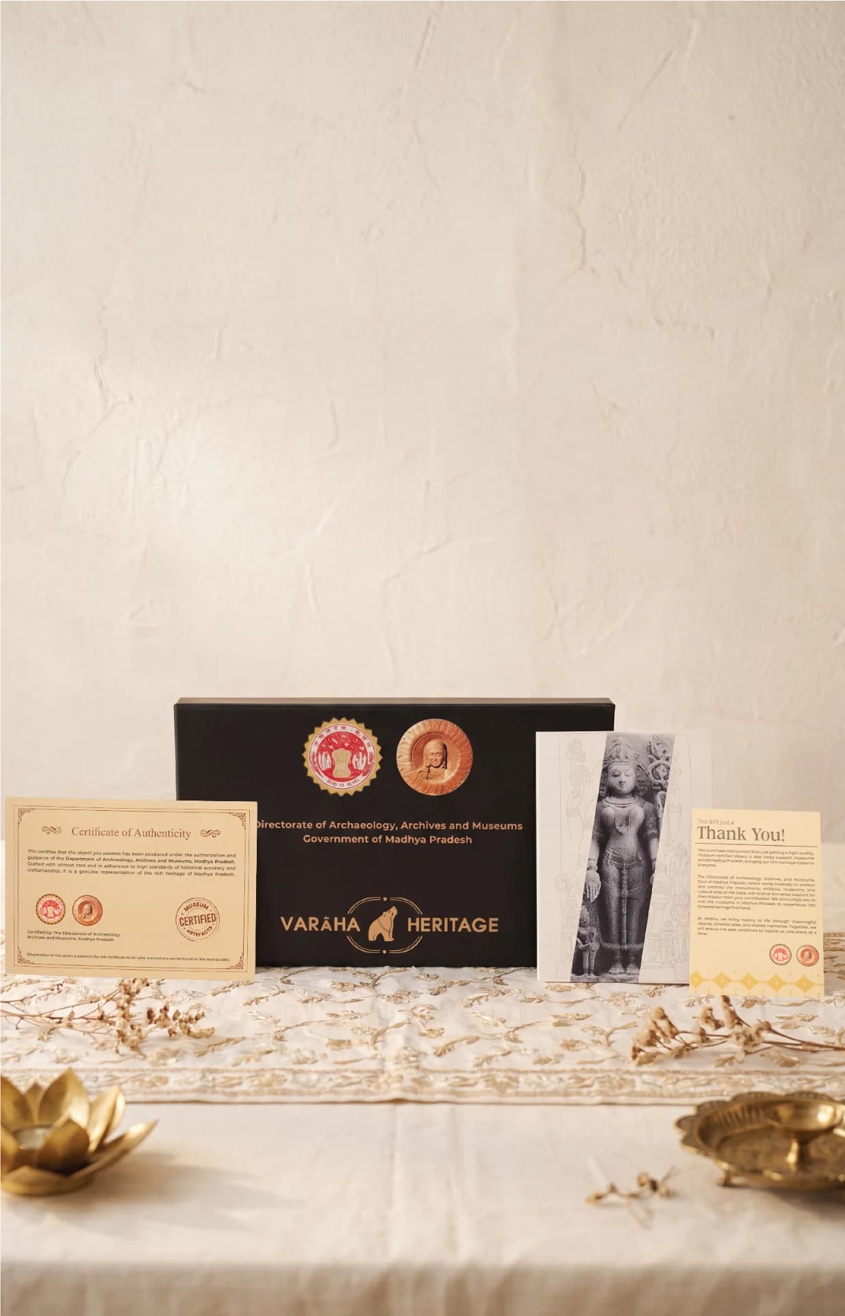 The Gauri Parvati Sculpture packaging set featuring a certificate of authenticity, branded display box, and informational card on a table.