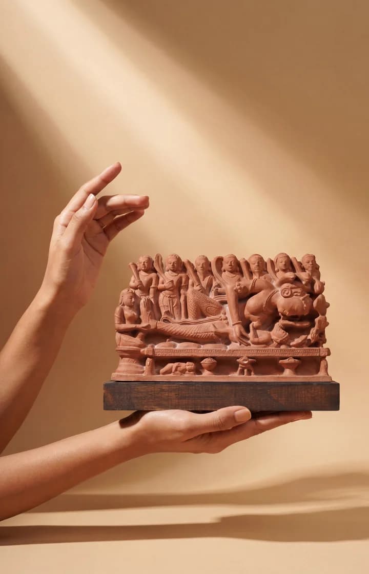 Hands gently cradle the Krishna's Birth Sculpture, a terracotta-style museum replica featuring intricate figures of Devaki and prison guards.