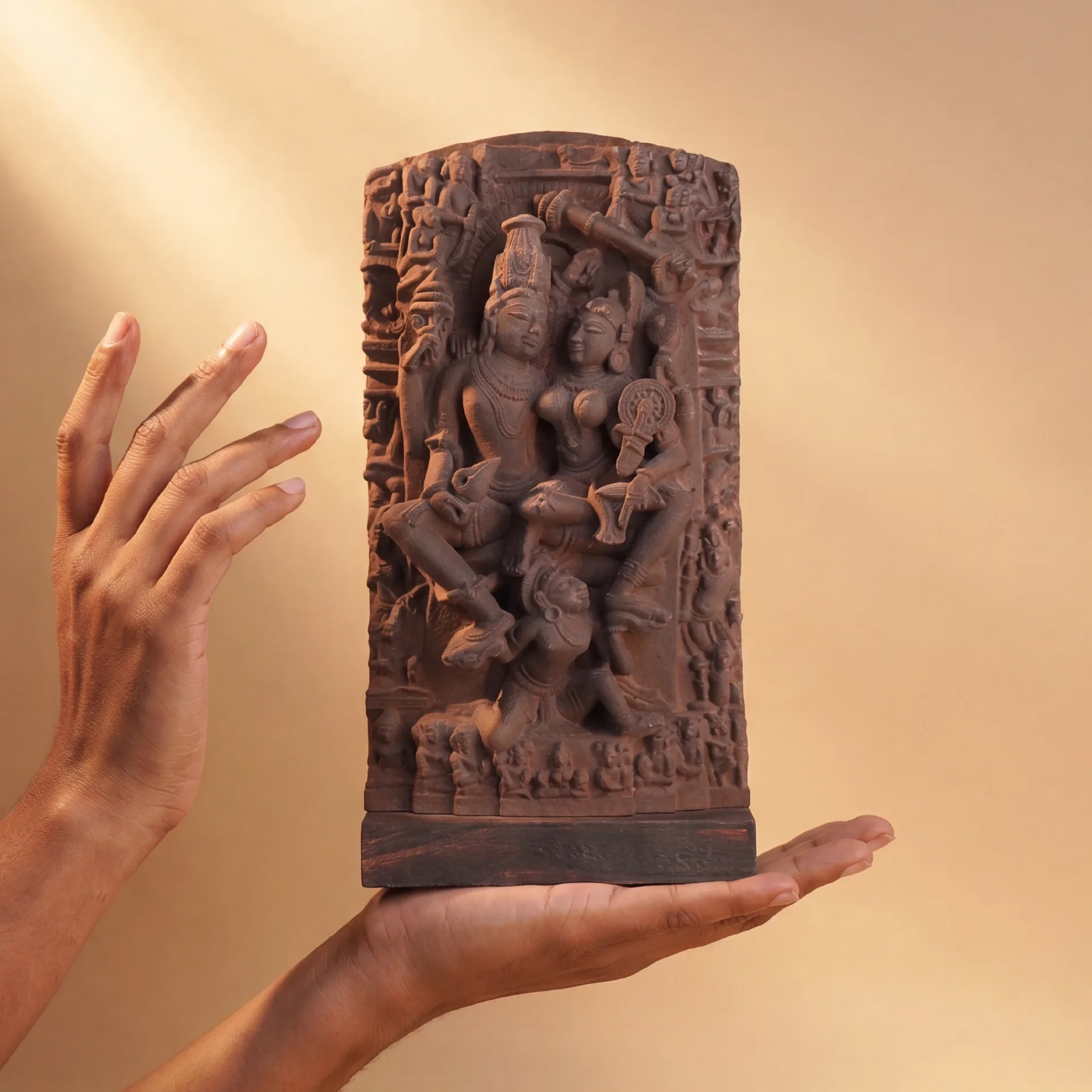 A pair of hands gently cradles the Lakshmi Narayan Sculpture, a detailed stone-finish replica showcasing intricate 12th-century Indian craftsmanship.