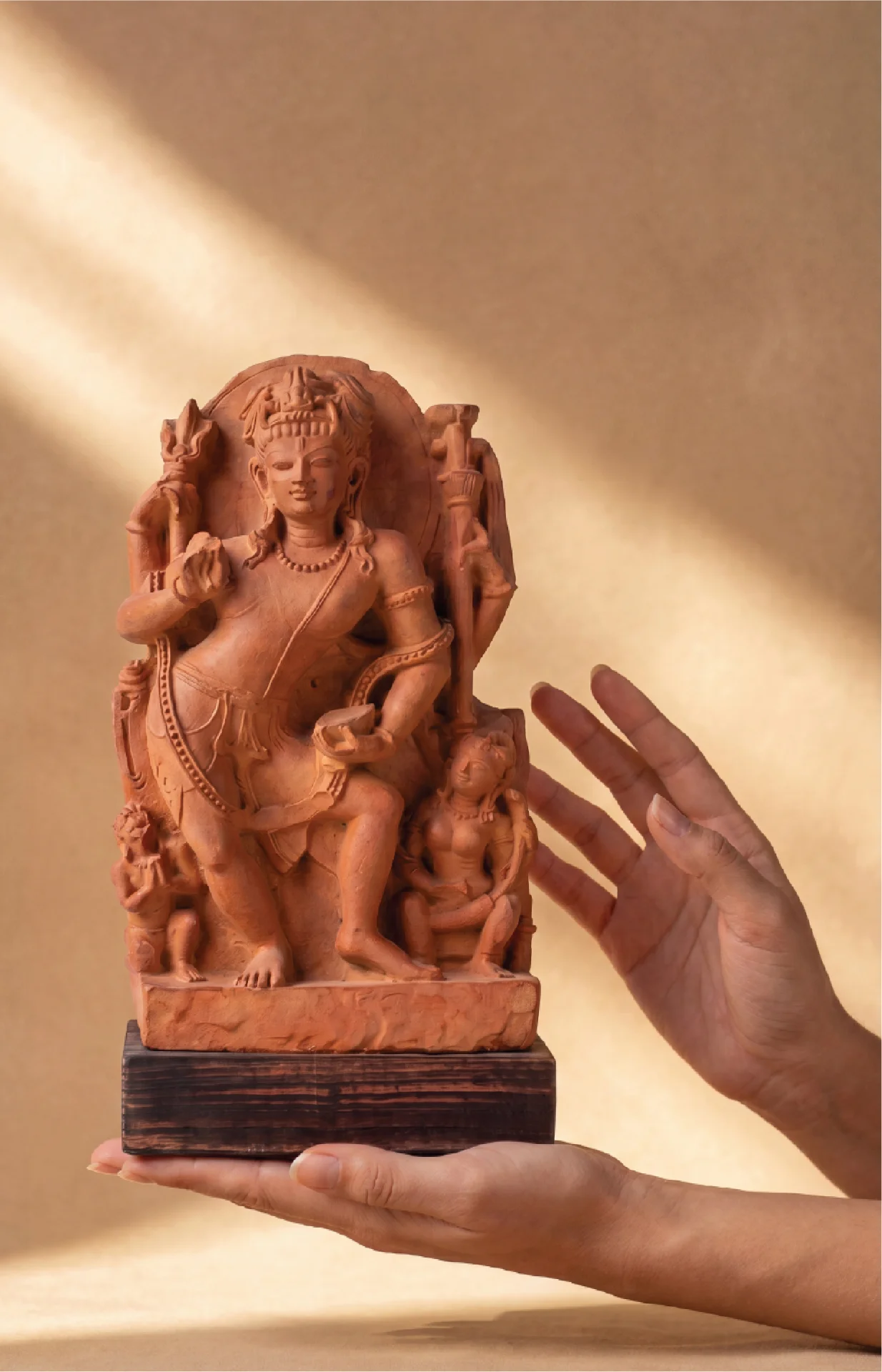 Hands hold a stone composite Natesh Shiva Sculpture, showcasing the intricate Pratihara style carving against a dark background.