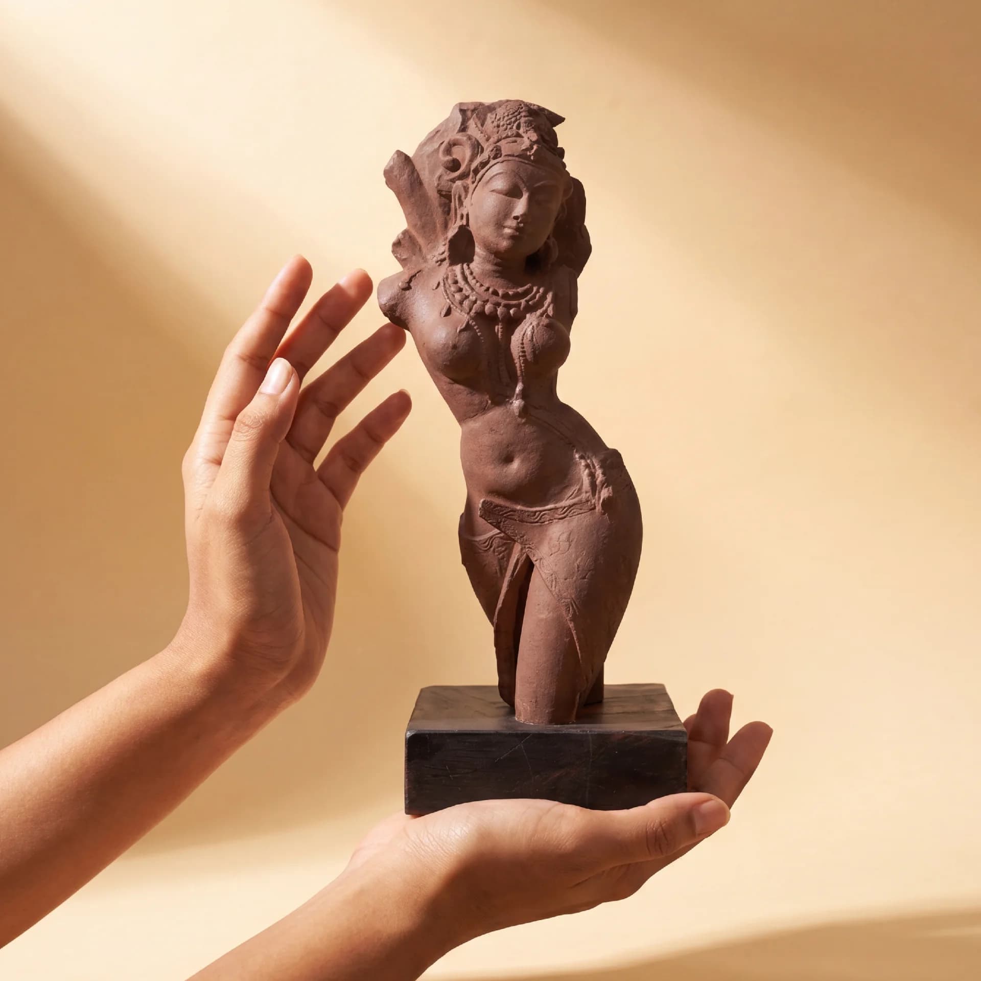 A pair of hands gently cradles a stone composite Salabhanjika Sculpture, highlighting the intricate craftsmanship of this museum-replica art piece.
