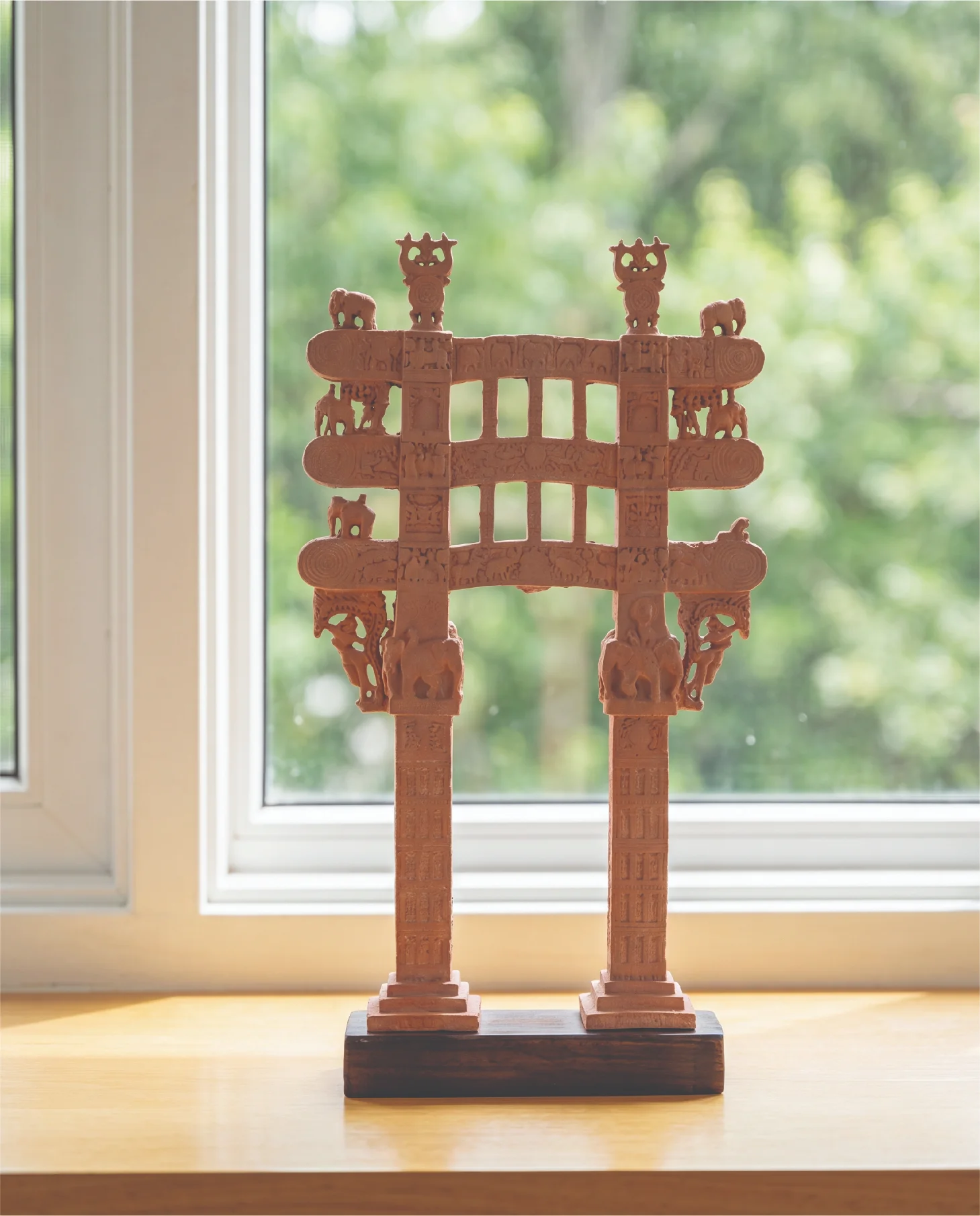 A front-facing view of the Sanchi Torana Gateway Miniature, a detailed stone composite replica standing on a wooden base.