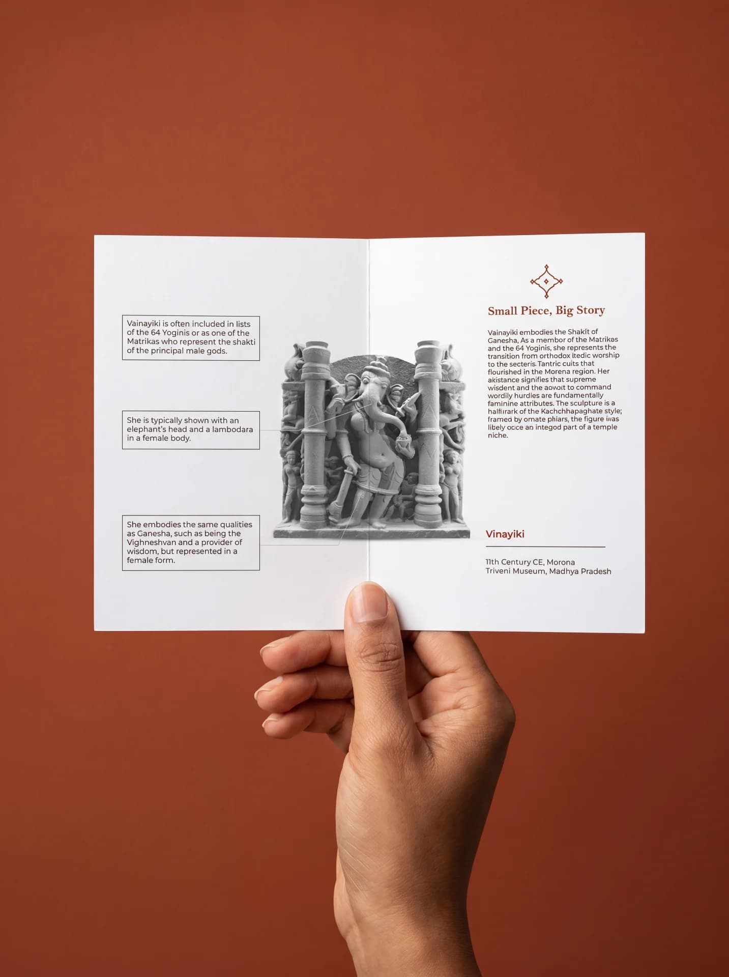 A hand holds an informational brochure featuring the Vinayaki Sculpture, showcasing detailed historical context and artistic analysis of this museum-grade replica.